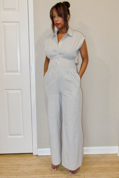 Woman wearing a striped jumpsuit standing in a room with a white door and light-colored floor.